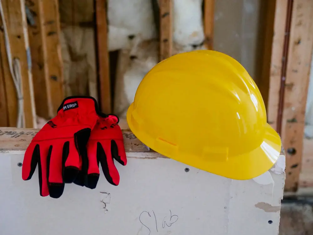 Kask ochronny i rękawice robocze leżące na drewnianym blacie
