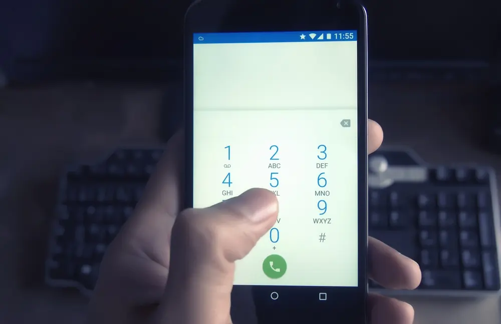 Dłoń trzymająca smartfon podczas wybierania numeru